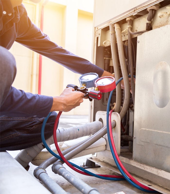 HVAC technician using pressure gauges and hoses to service an air conditioning unit, emphasizing expertise in air conditioning repair in Lodi for residential and commercial systems.