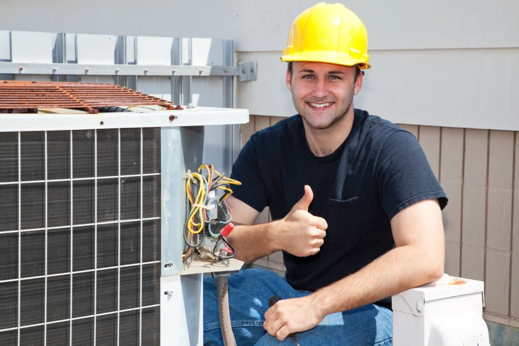HVAC technician giving a thumbs up next to an air conditioning unit, highlighting HVAC upgrades for improved indoor air quality.