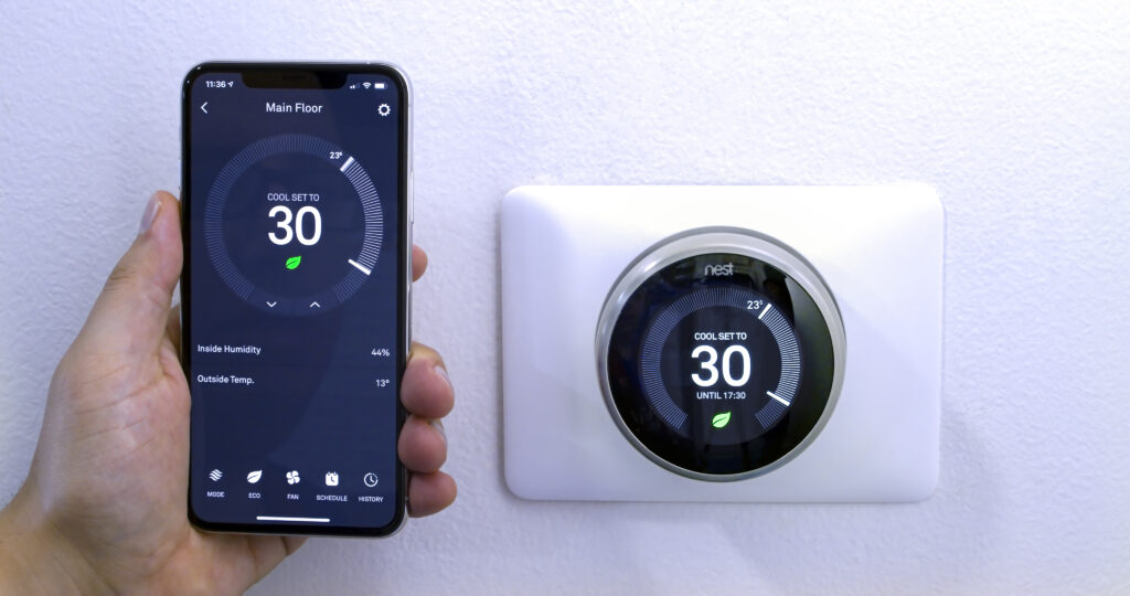 Smart thermostat display with mobile app interface showing temperature settings and HVAC controls for efficient home climate management.