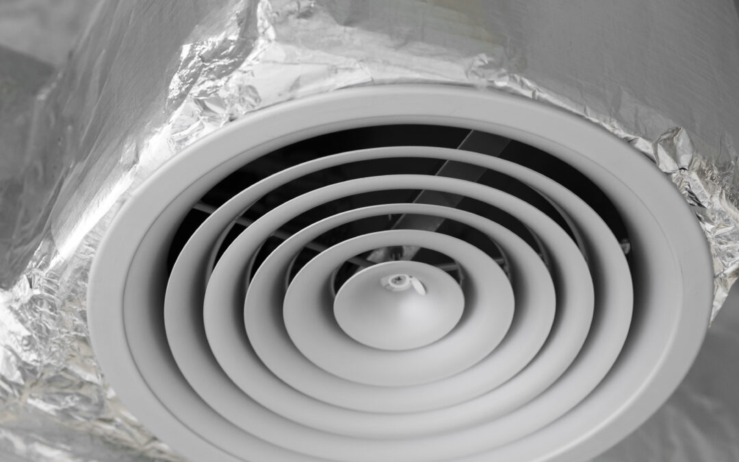 Air vent with circular grille and spiral design, surrounded by ductwork, illustrating airflow solutions for HVAC systems and indoor air quality.